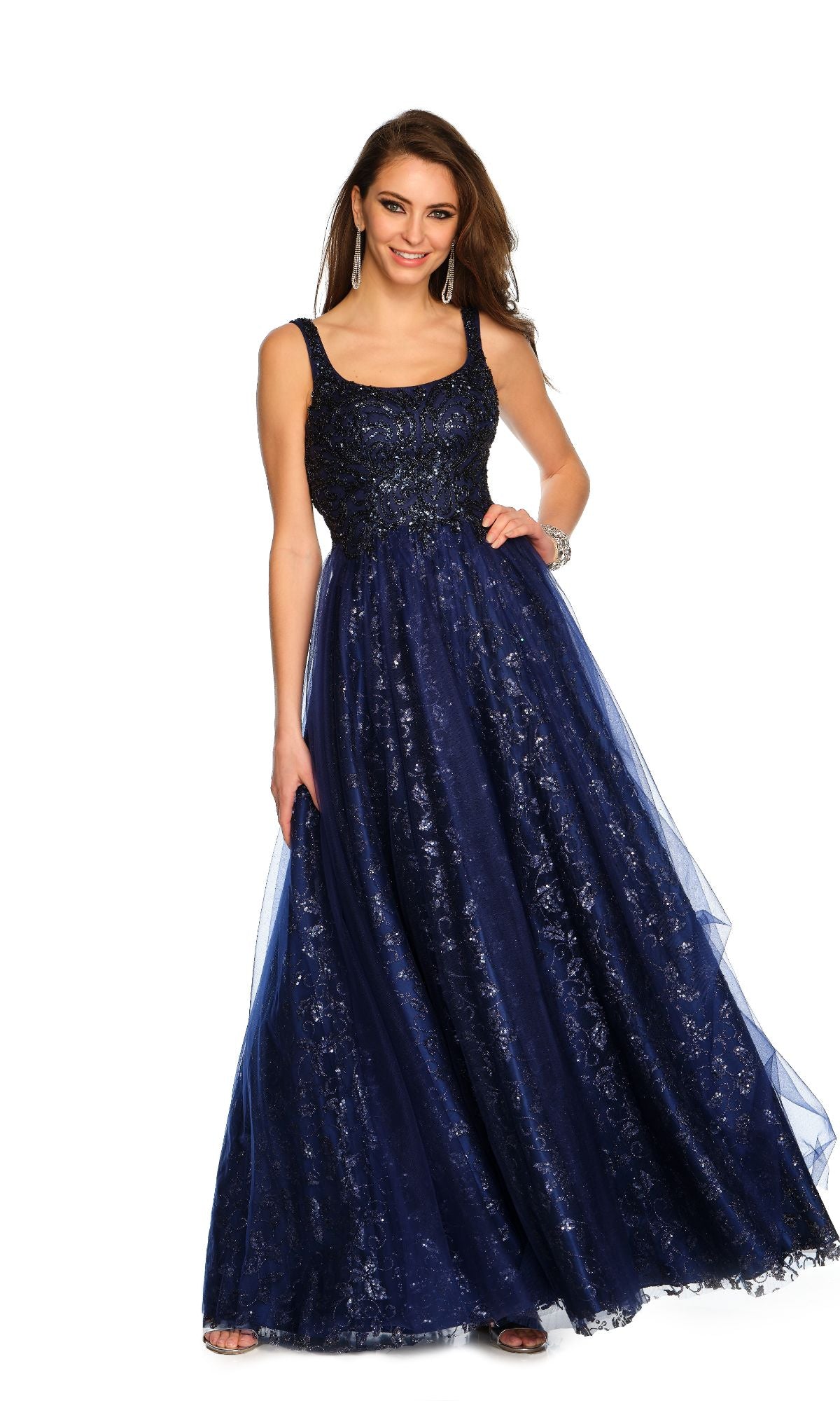 A woman wearing the Dave and Johnny Navy Long Glitter Prom Dress 11008, featuring a sleeveless fitted sequined bodice and flowing floor-length a-line skirt, stands against a white background.